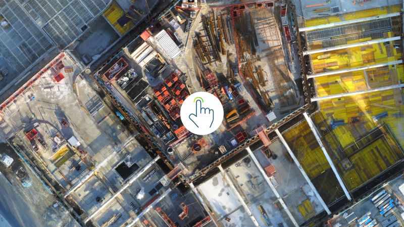 Top-down drone view of construction site with interactive pointer overlay.