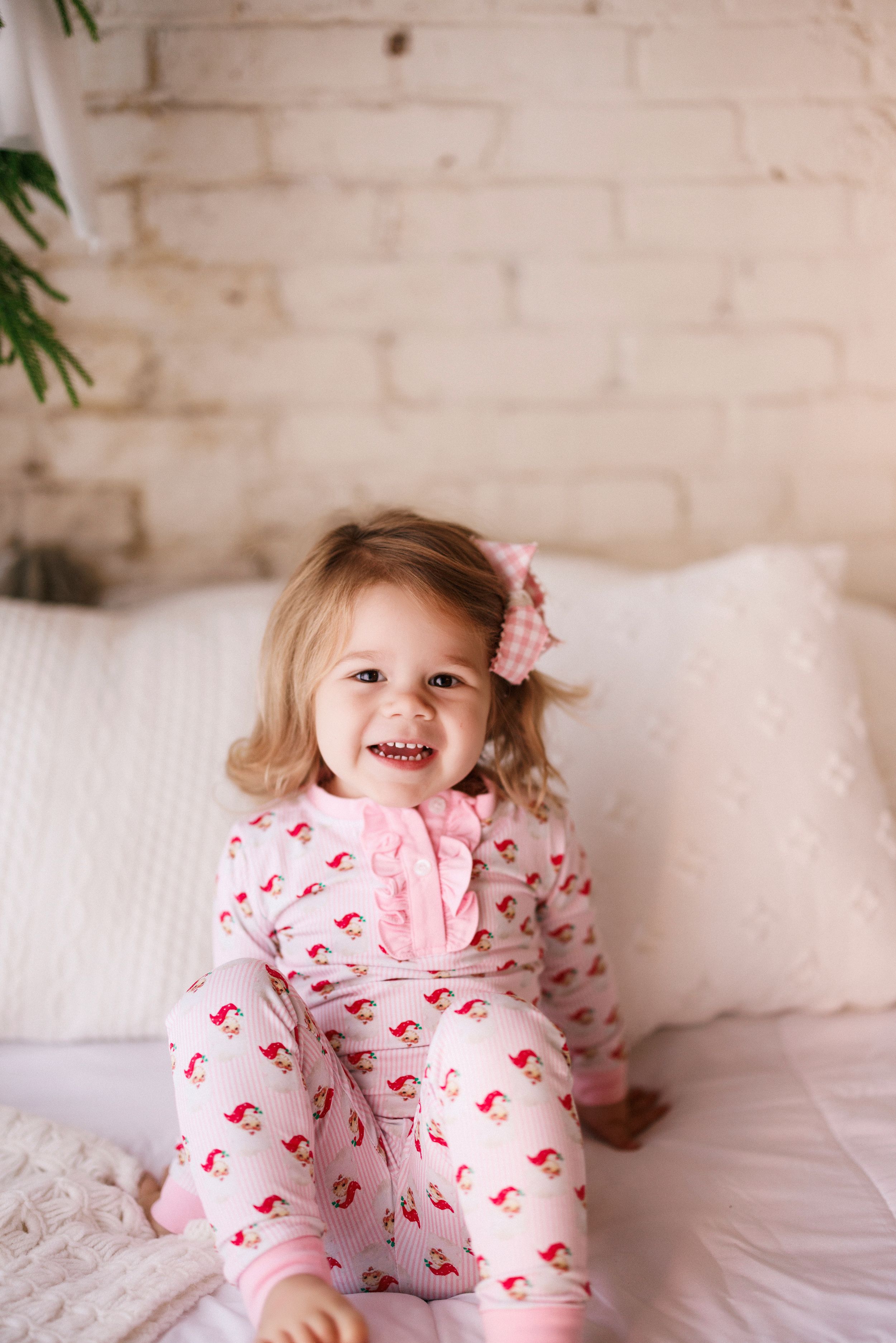 A series of photos showing a child in pink flamingo print pajamas playing and jumping on a white bed.
