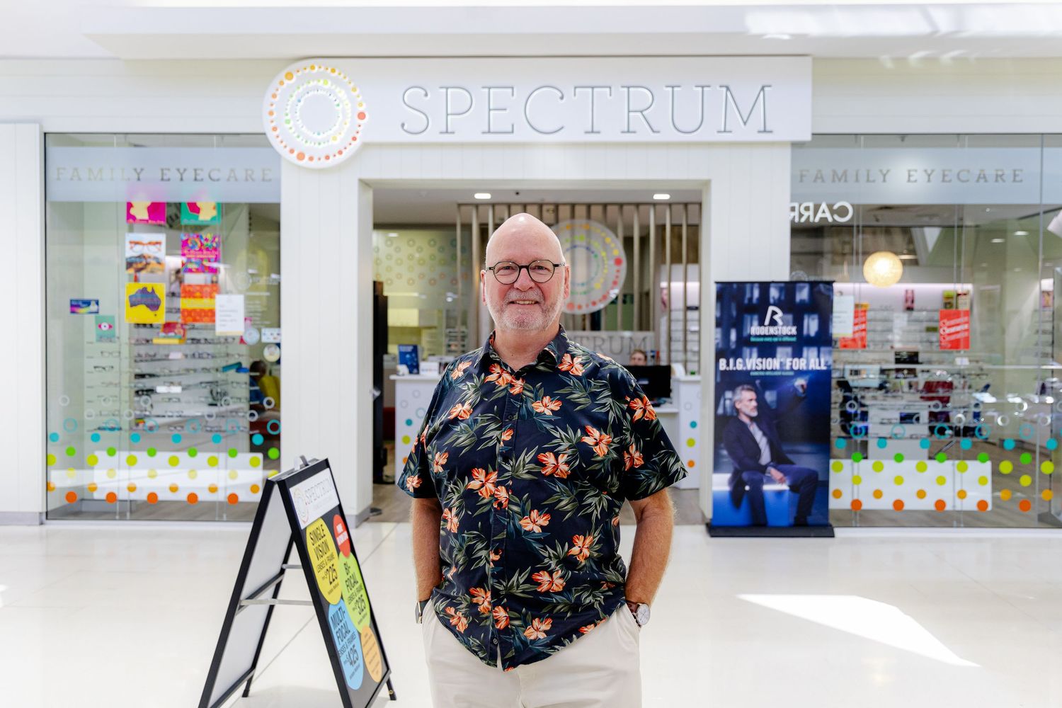 A modern storefront with glass windows displays a sign reading 'Spectrum' in a shopping center.