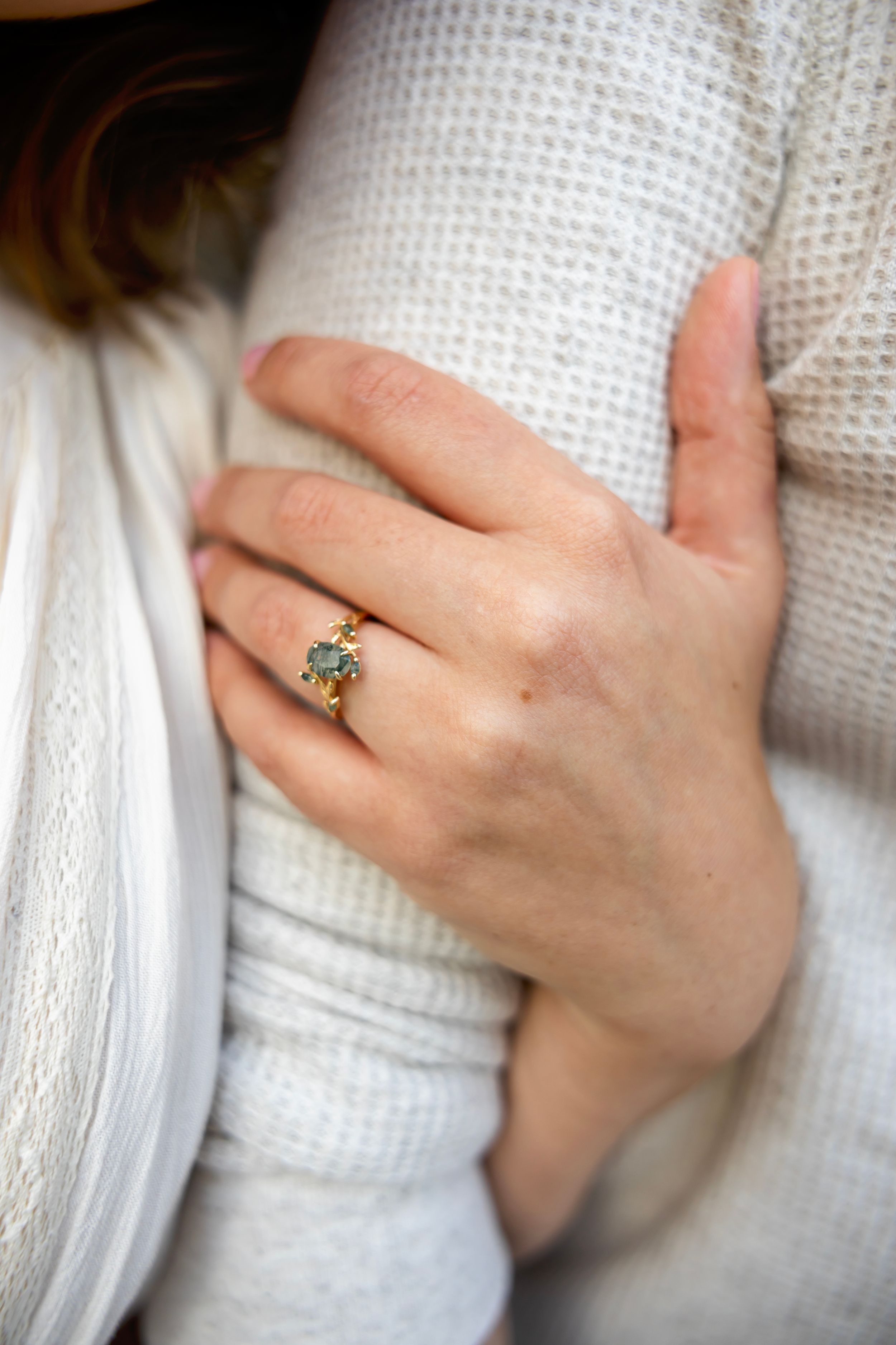 A series of close-up shots showing hands wearing a white knit sweater and delicate ring against a soft textured background.