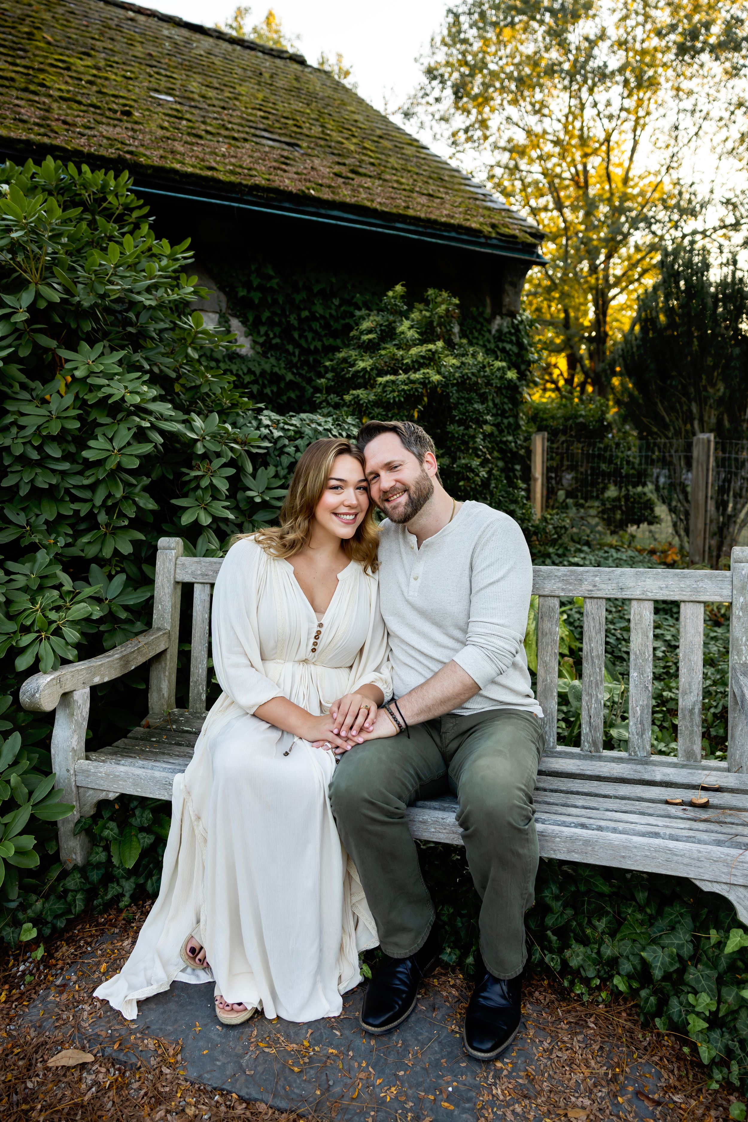A couple shares tender moments together while sitting on a rustic wooden garden bench during an autumn evening.