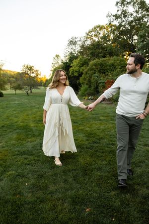 A couple dances playfully together on a grassy lawn during golden hour.