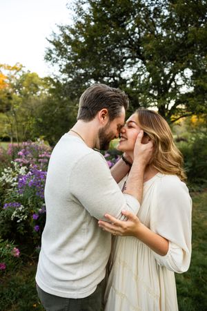 A tender moment between a couple surrounded by blooming flowers in a garden at sunset.