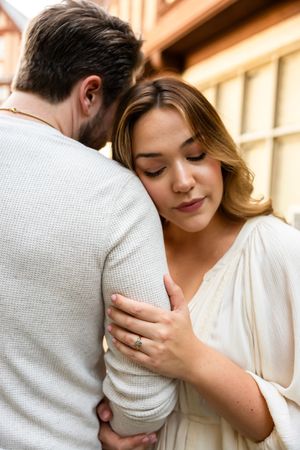 Intimate close-up portrait showing tender embrace against warm sunlit background.