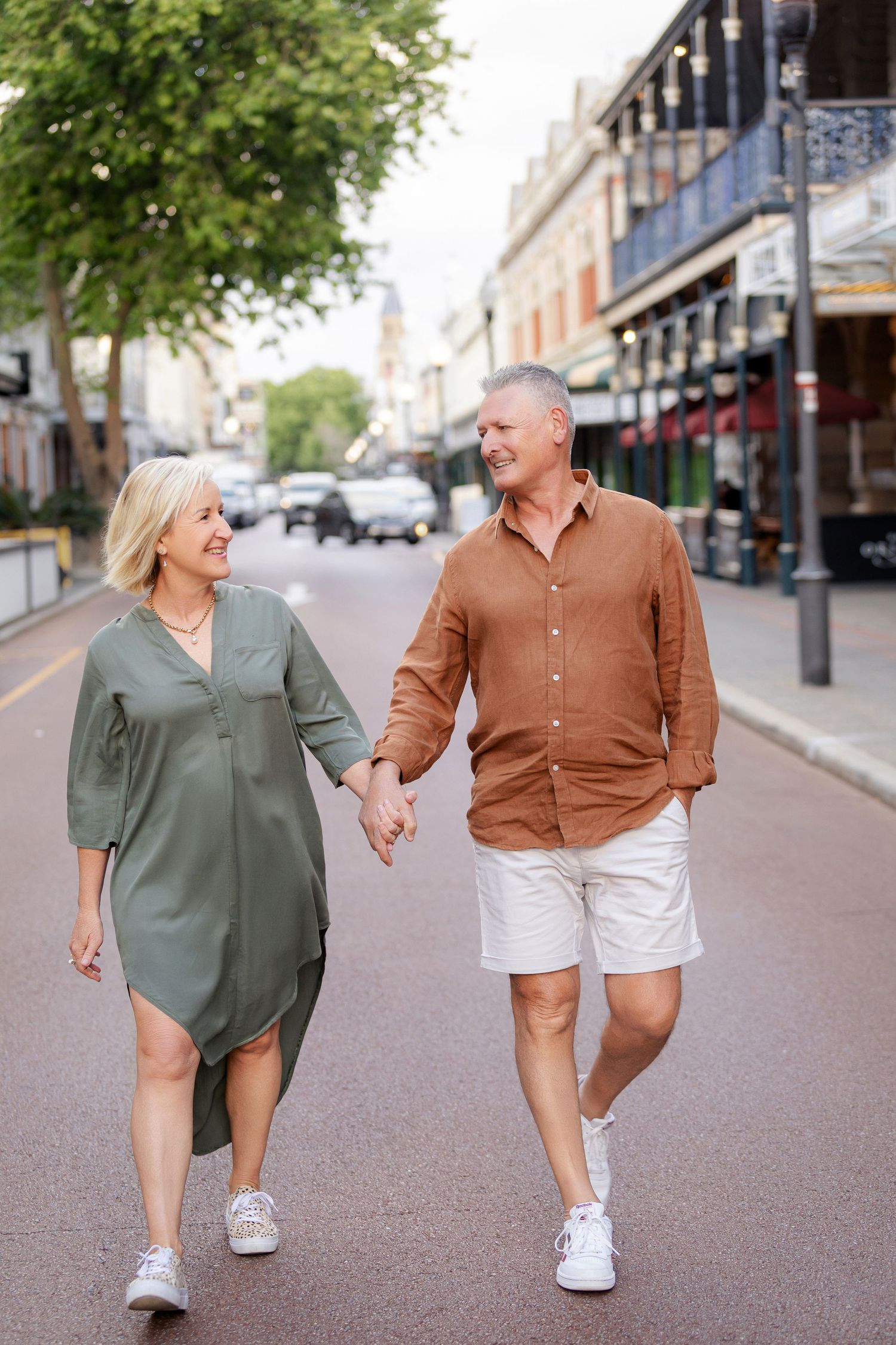 A couple walking and laughing together on a charming urban street during a casual daytime stroll.
