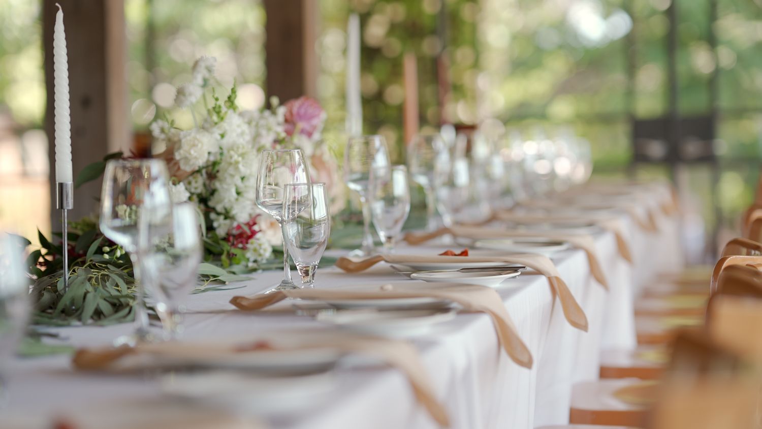 Elegant wedding table setting with white linens, floral centerpieces and glassware.