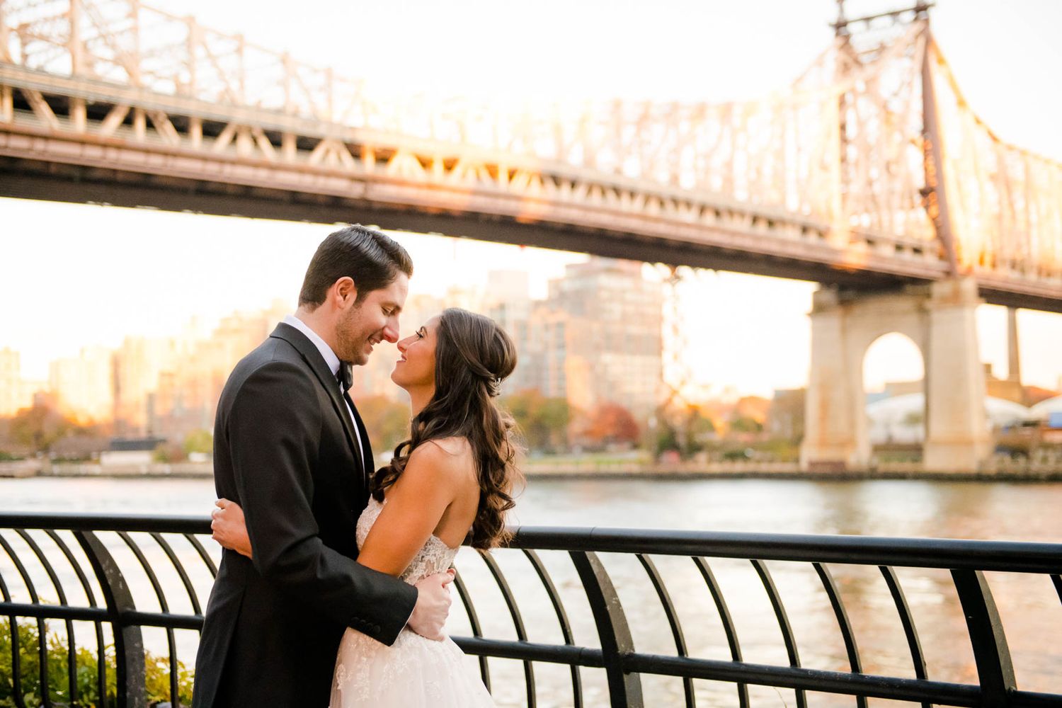 Couple sharing romantic moments along the Queensboro Bridge in New York City during golden hour.