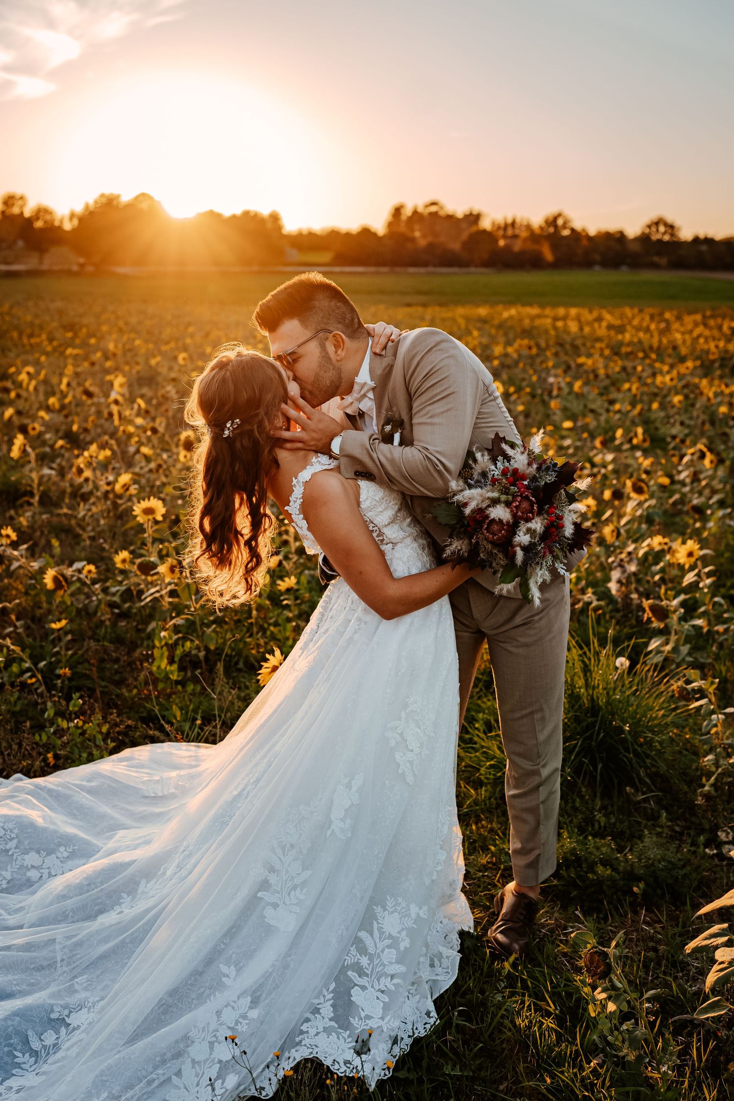 A romantic couple in white clothing shares an intimate moment in a wooded setting during golden hour.