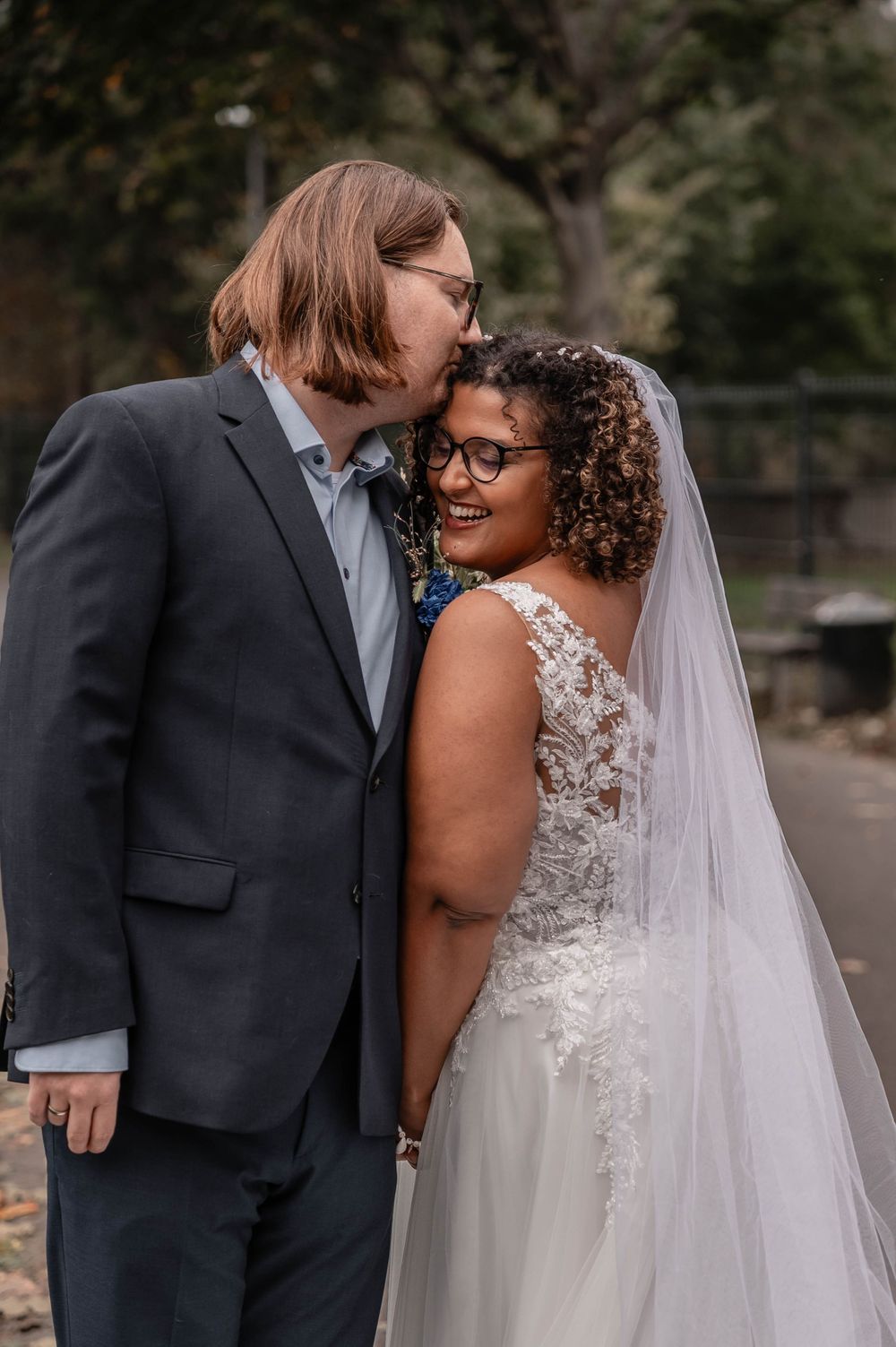 A happy couple shares intimate moments and laughter during their wedding photo session in an outdoor setting.