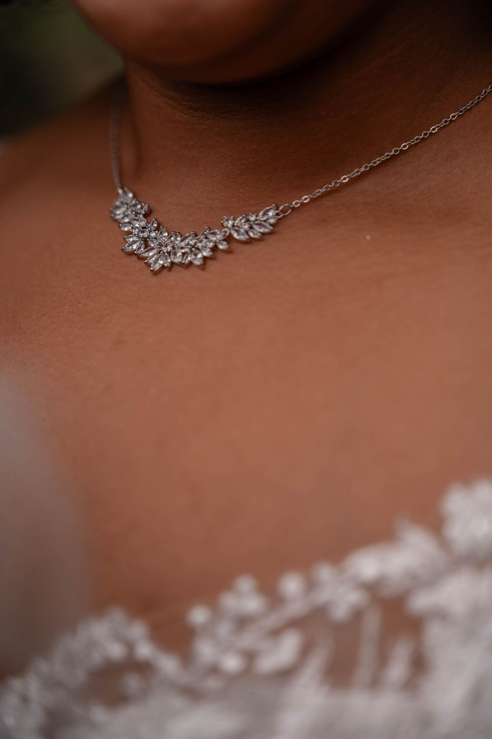 Close-up view of a delicate silver necklace with crystal floral details worn against skin.
