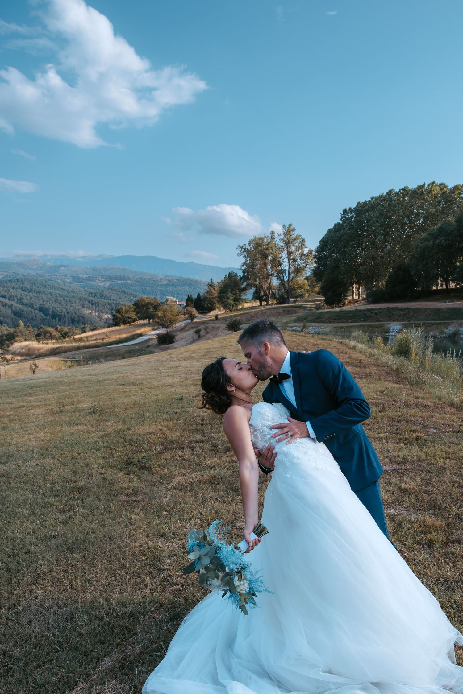 Wedding couple embracing in dramatic dips against rolling hillside landscape. Domaine la Plume photographe mariage