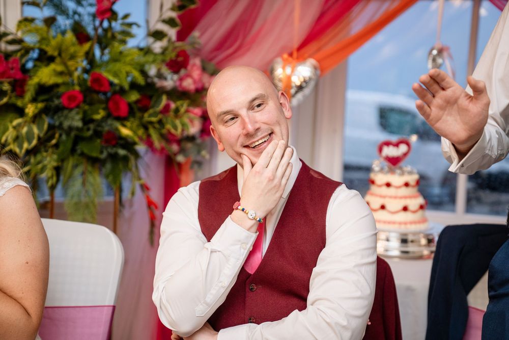 Wedding guests share joyful laughter during a reception celebration at an elegantly decorated venue.