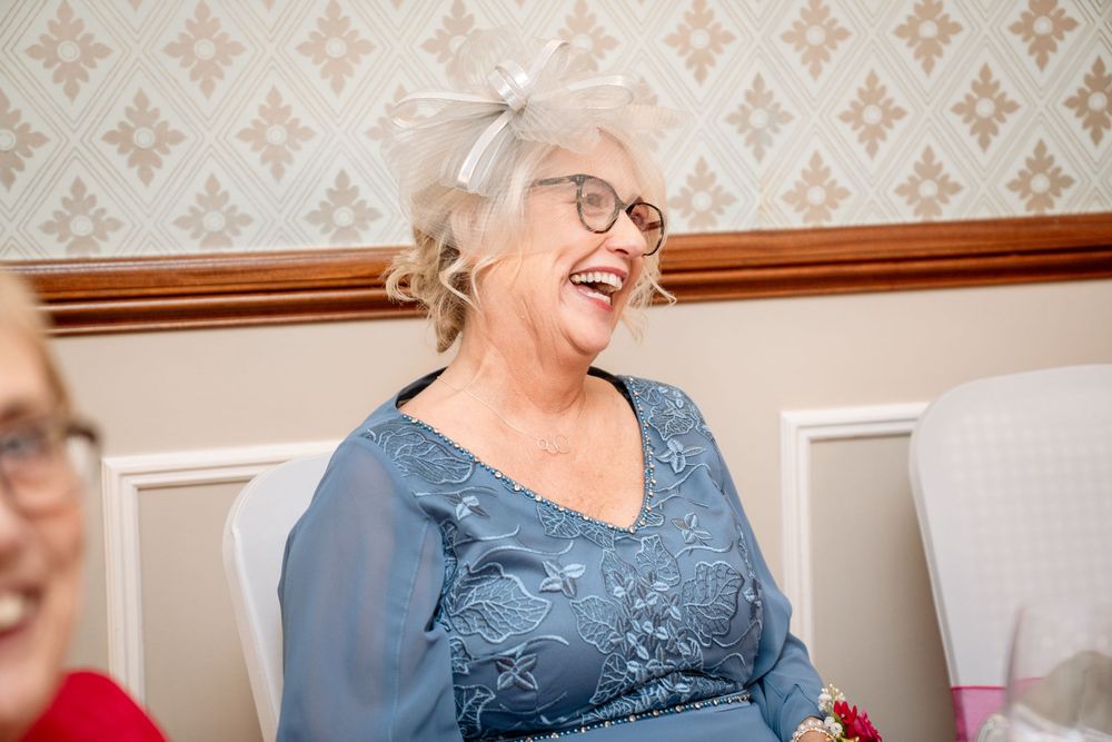Senior resident in blue dress enjoys activities at assisted living facility with warm smiles and engagement.