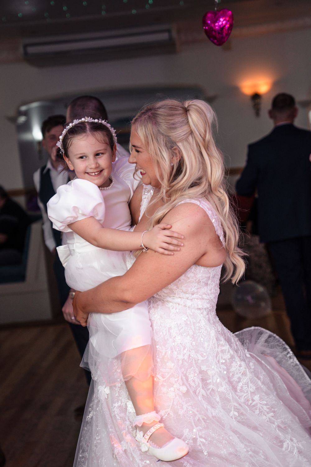 A tender moment between two people in white dresses dancing together at a formal event.