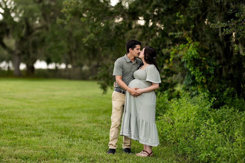 A couple shares tender moments in a lush green park setting during their engagement photo session.