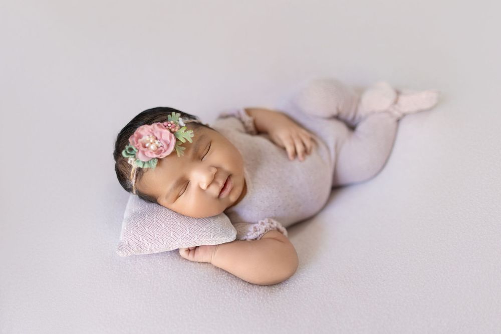 Newborn baby sleeping peacefully on soft gray blanket in gentle curled position.