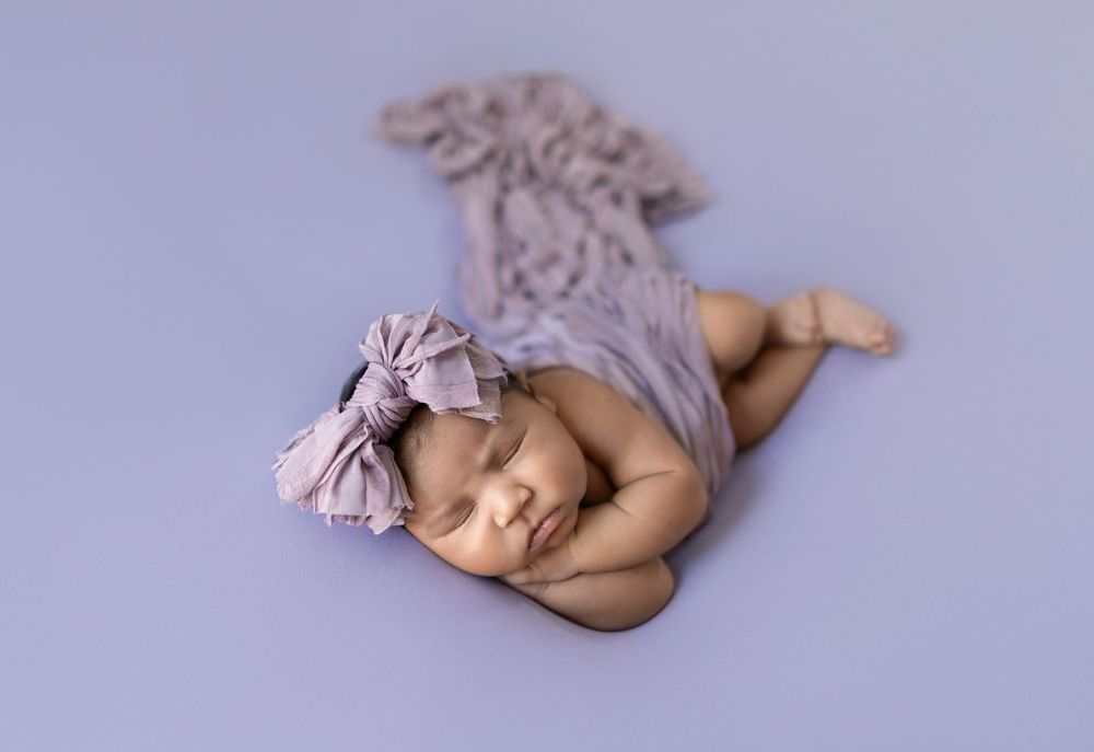 A series of seven soft pastel purple newborn photography poses showing a sleeping baby in artistic positions.