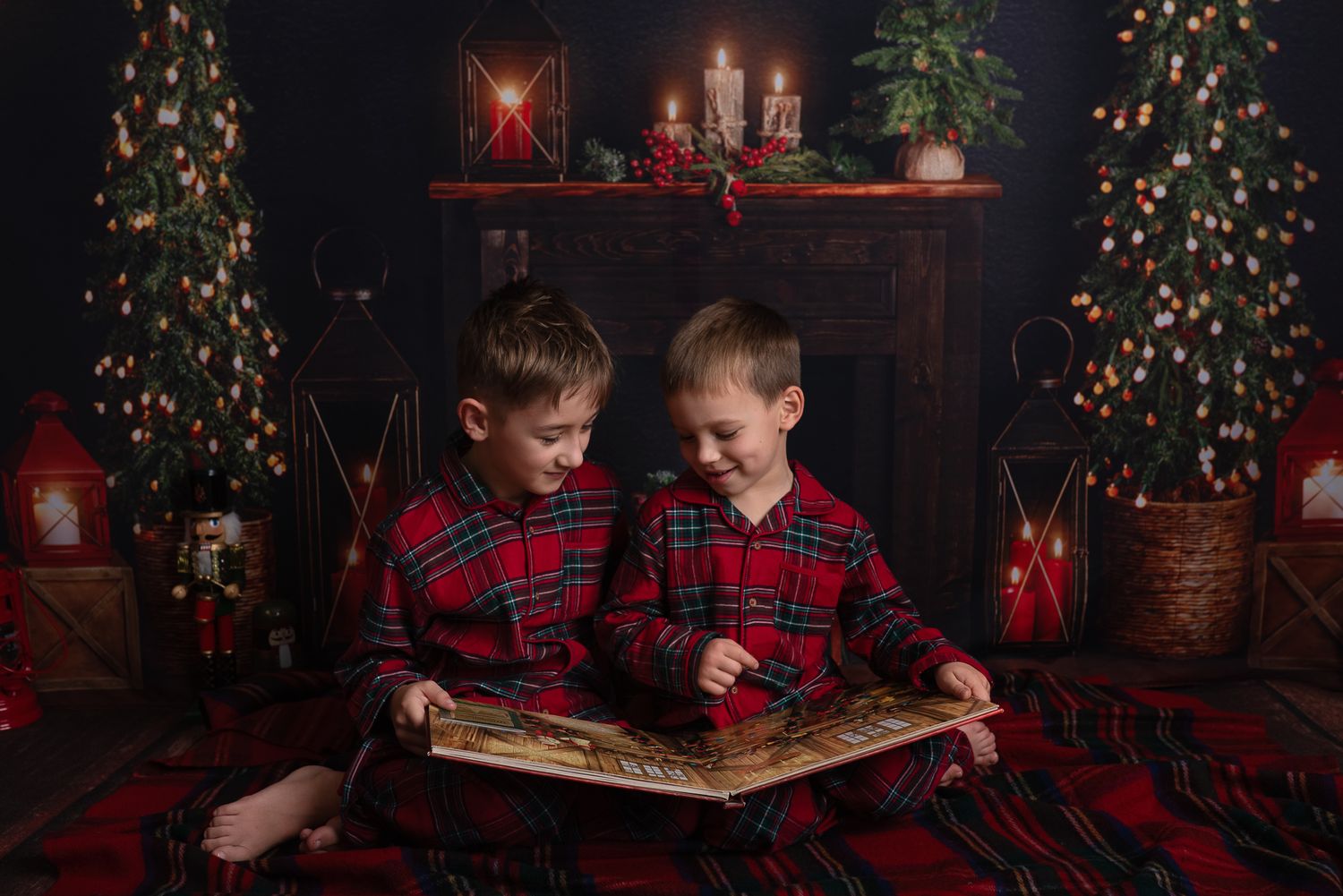 Children in matching plaid outfits sit by a Christmas tree in a cozy room with festive holiday decorations.