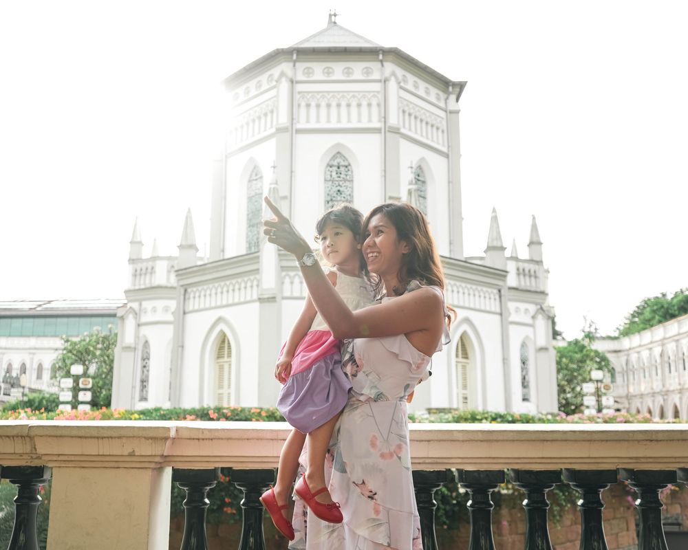 A group of people taking photos at a white church or cathedral with ornate architecture and towers in the background.