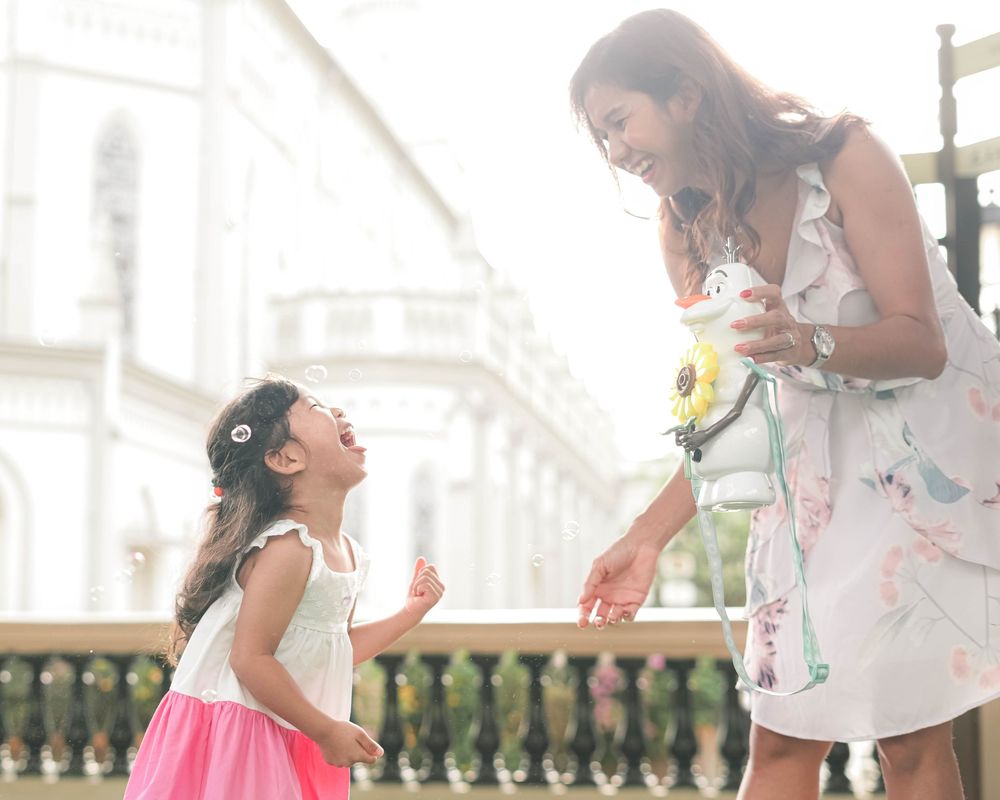People share laughter and smiles during a festive outdoor gathering with white decor and natural lighting.