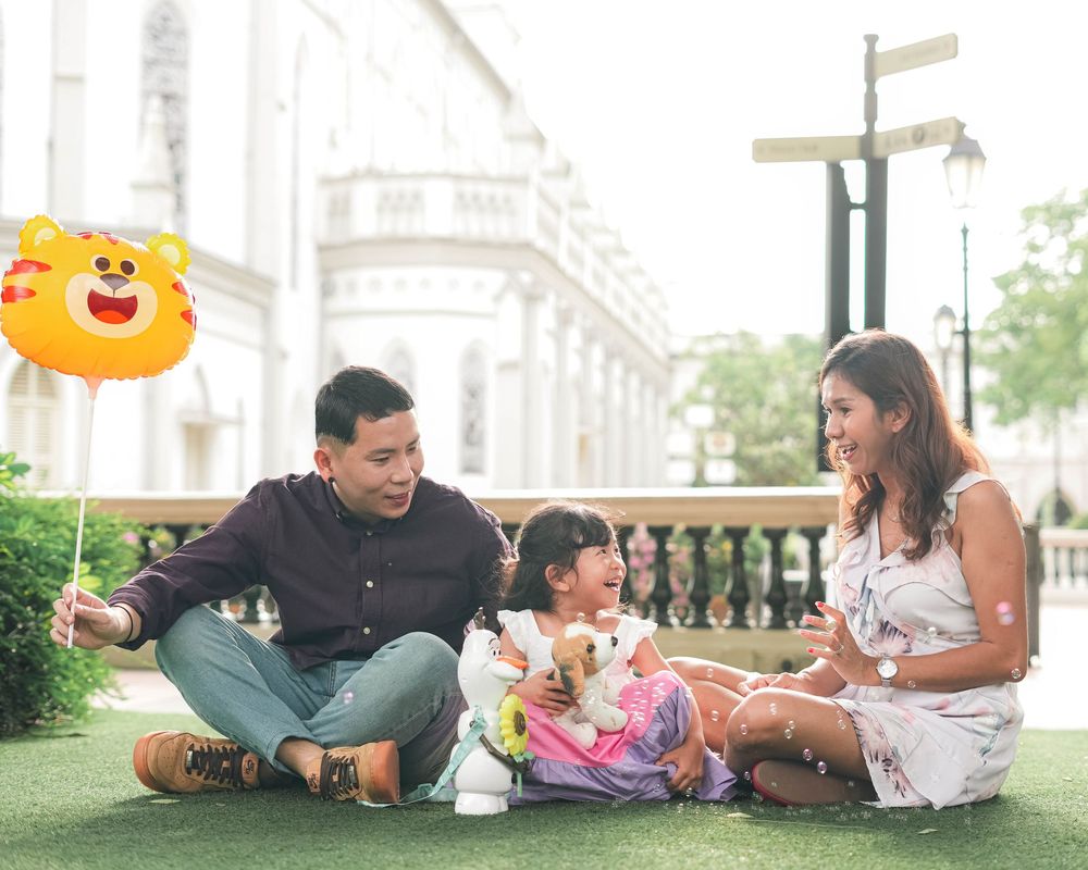 Family enjoying a picnic together on the grass while playing with toys and having fun outdoors.