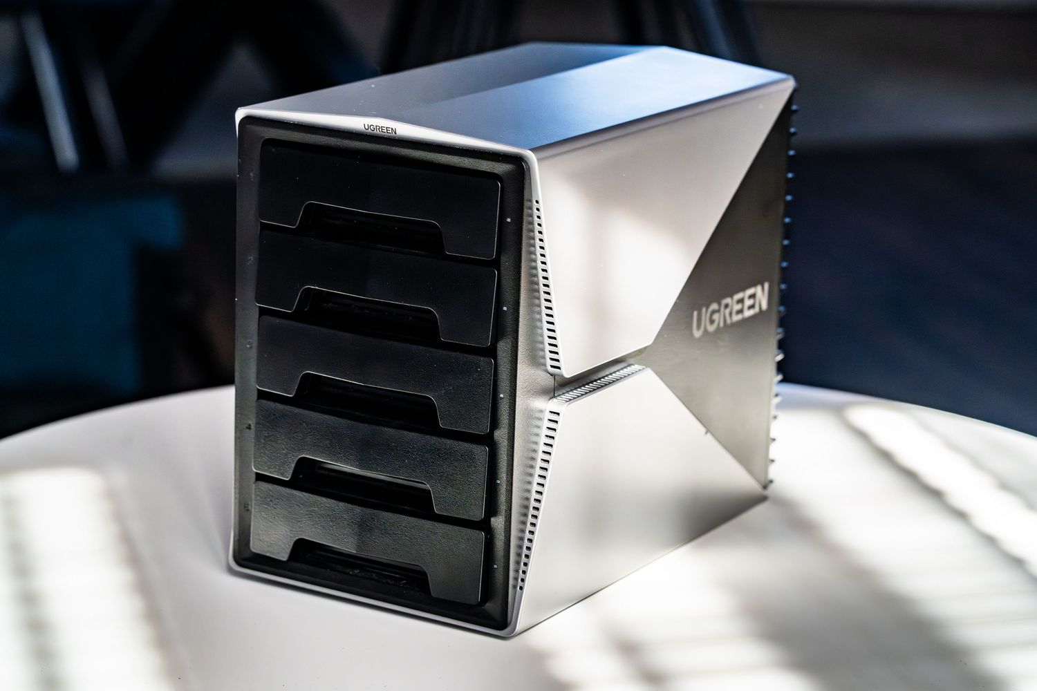 A modern silver desktop file organizer with multiple black trays sits on a white surface in natural lighting.