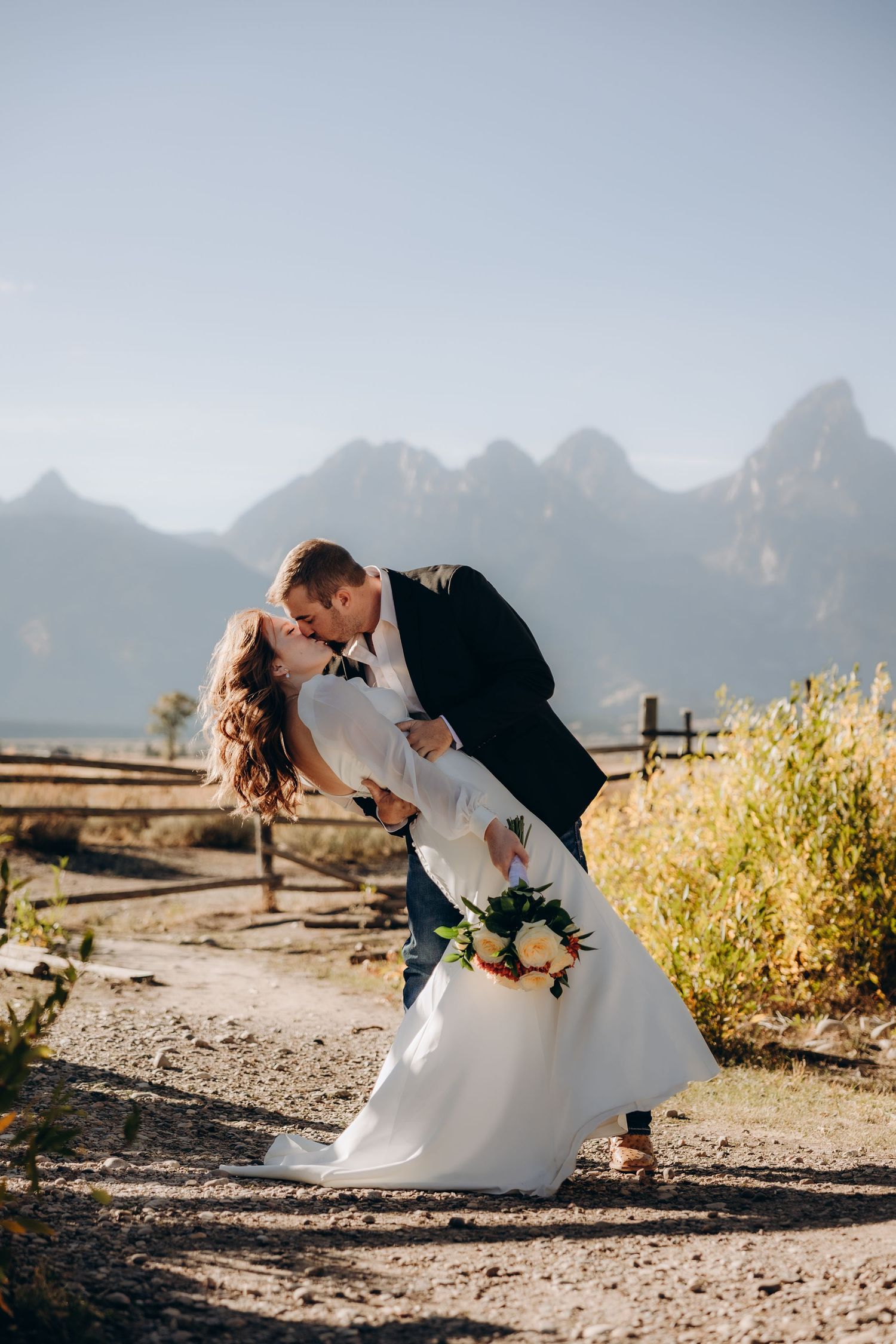 Romantic couple in wedding attire share intimate moments against a scenic mountain backdrop at sunset.