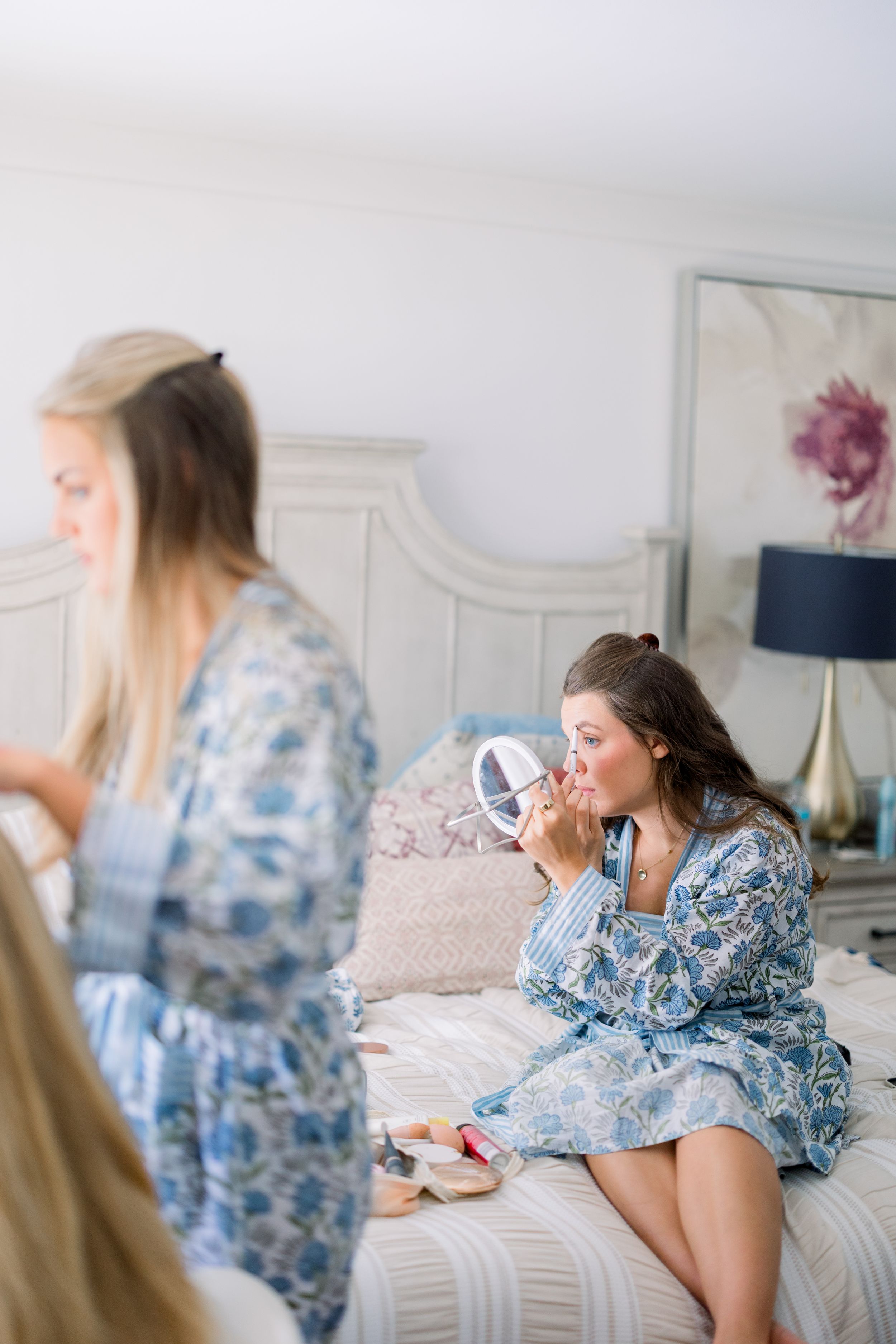 Bridesmaids in blue floral robes relax during wedding morning preparations.