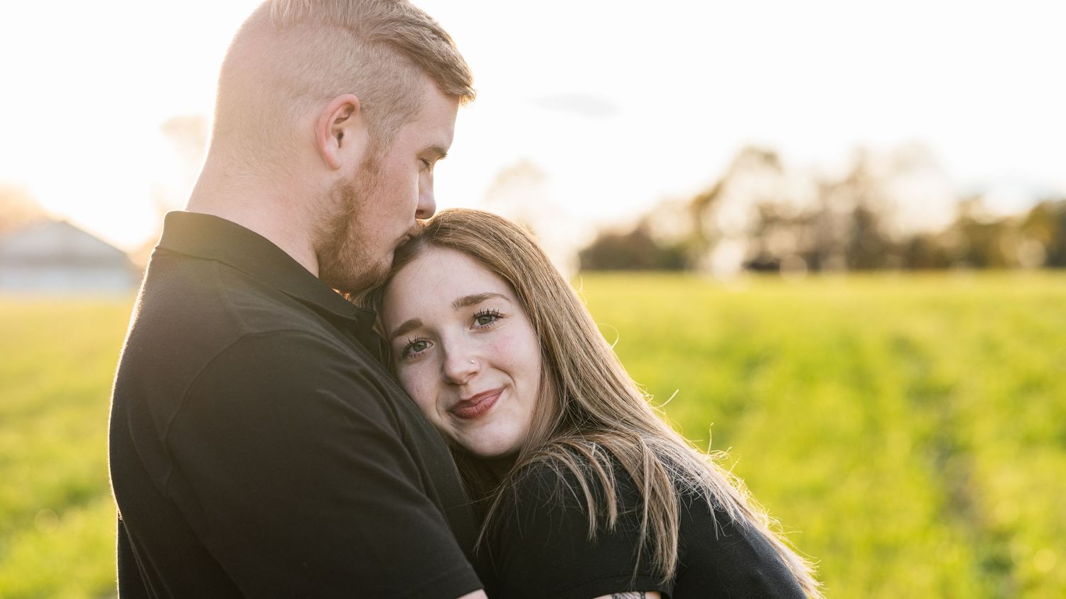 Intimate couple's portrait session in a sun-drenched field during golden hour.