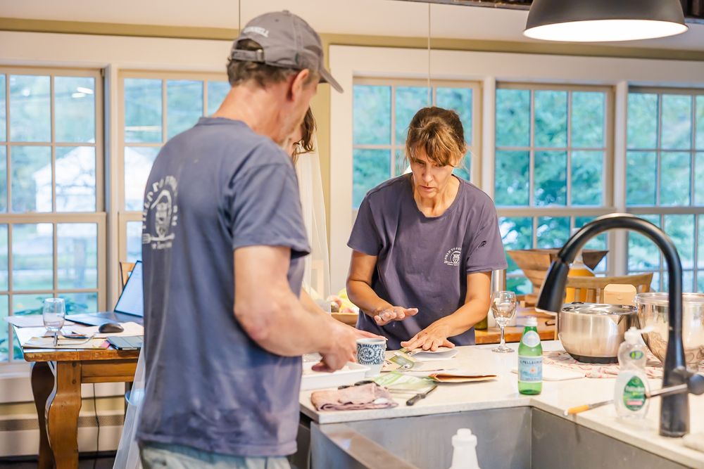 Students work together at tables in a bright classroom with large windows during an educational workshop session.