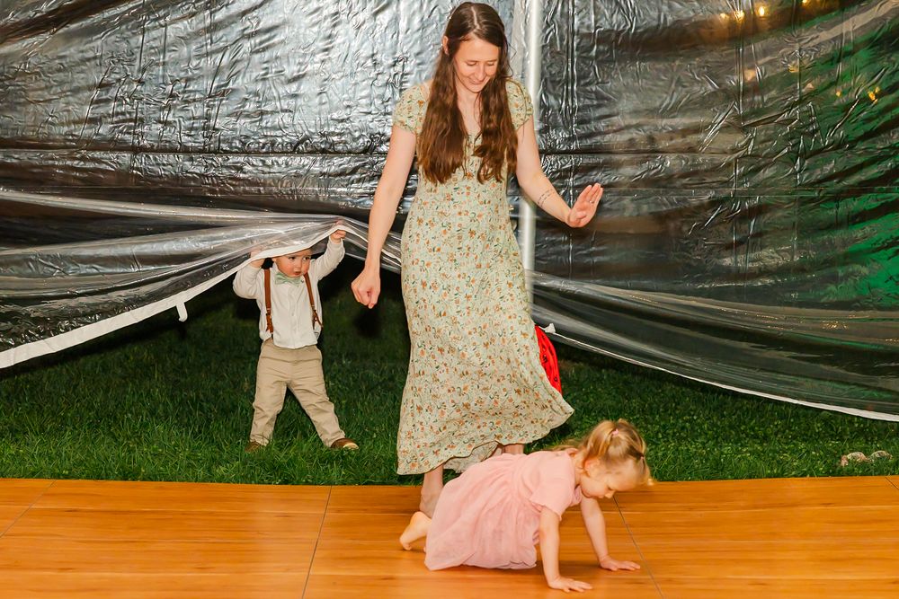 People dancing and having fun at a wedding reception under twinkling lights and draped fabric decor.