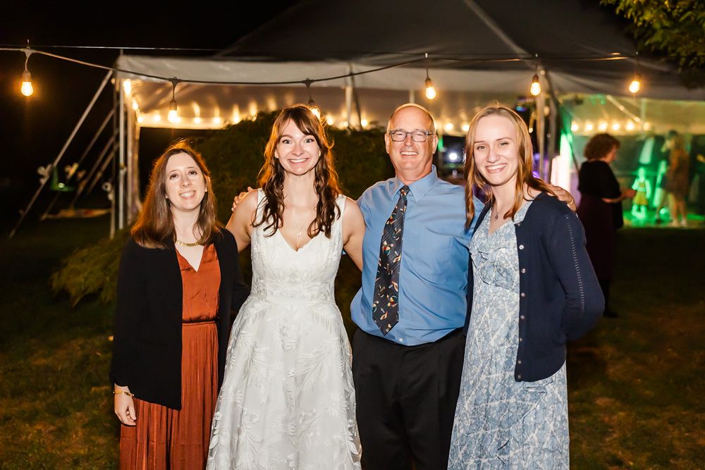 Guests mingling and celebrating at an outdoor wedding reception with twinkling lights and a white tent.