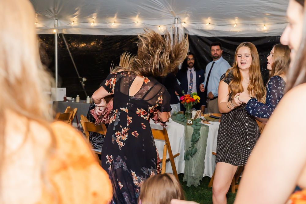 Wedding guests enjoying themselves on a dance floor under a tent with festive lighting.