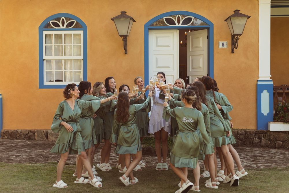 Students in green uniforms dance together in front of an orange building with colonial architecture.