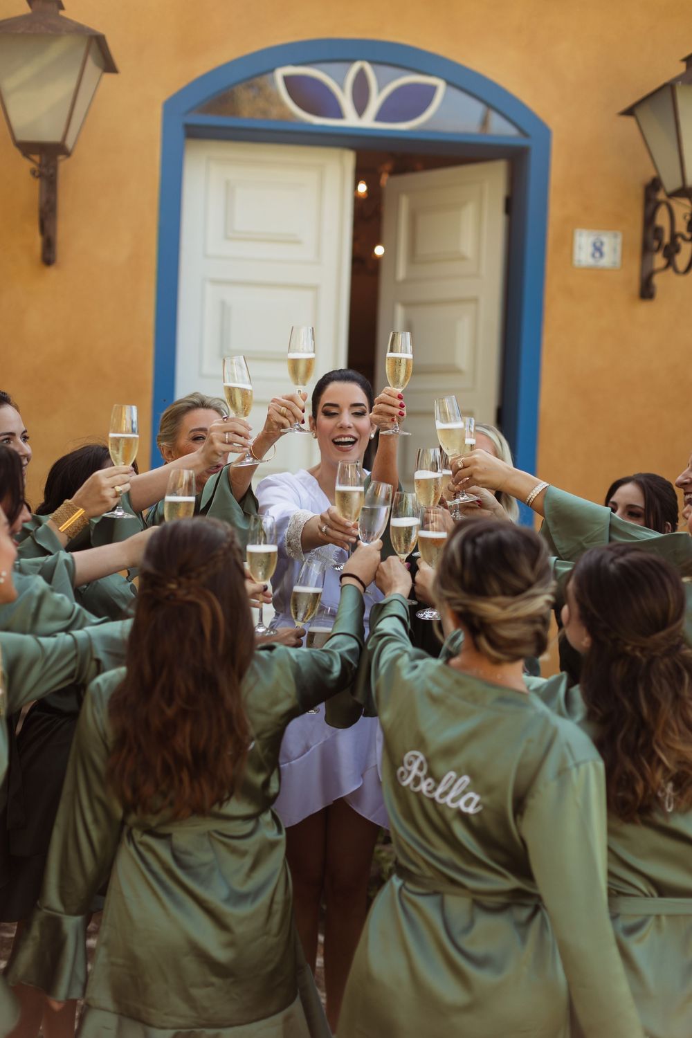 A group in matching green robes raising champagne glasses in a celebratory toast.