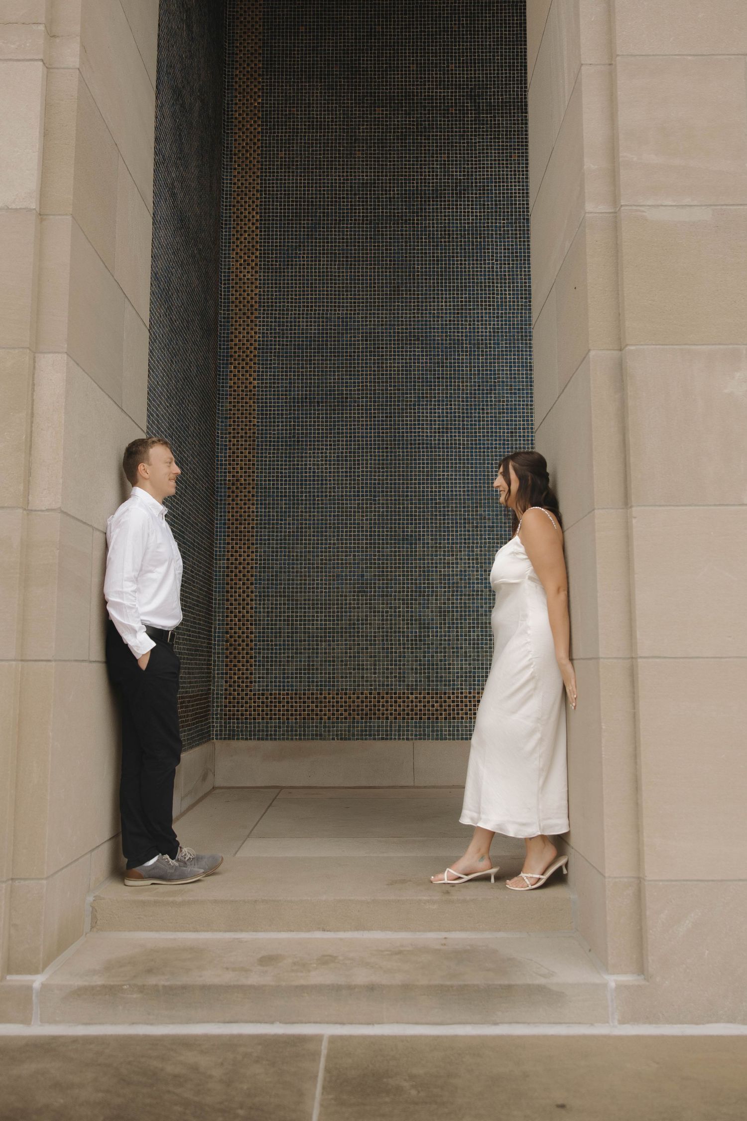 Minimalist wedding photo series showing couples' feet and legs against stone columns in an architectural setting.
