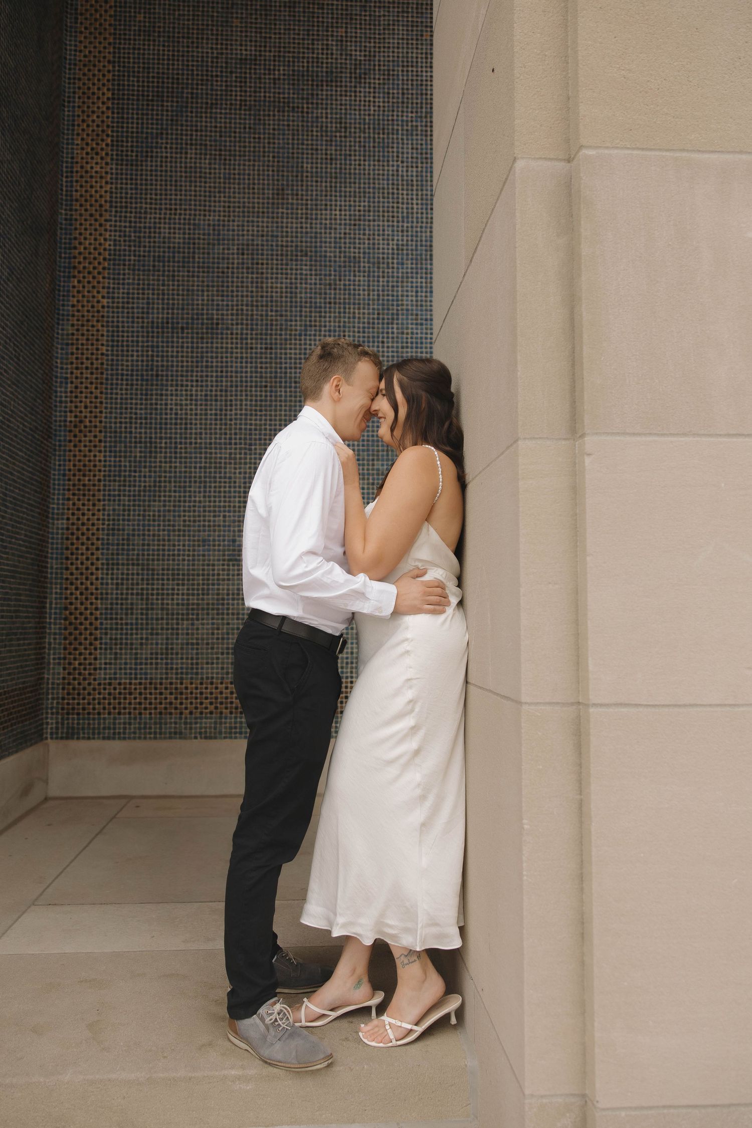 A couple shares an intimate kiss against a stone wall in a sequence of romantic photos.