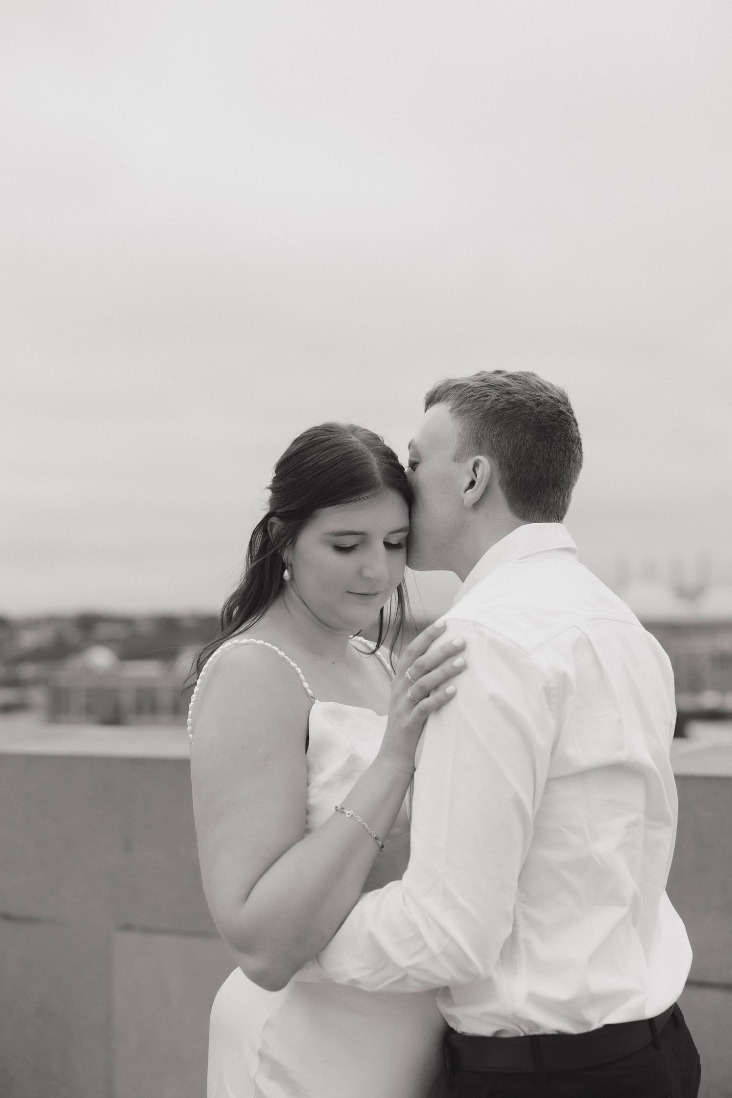 Black and white photo series showing a romantic kiss sequence between a couple on a rooftop.