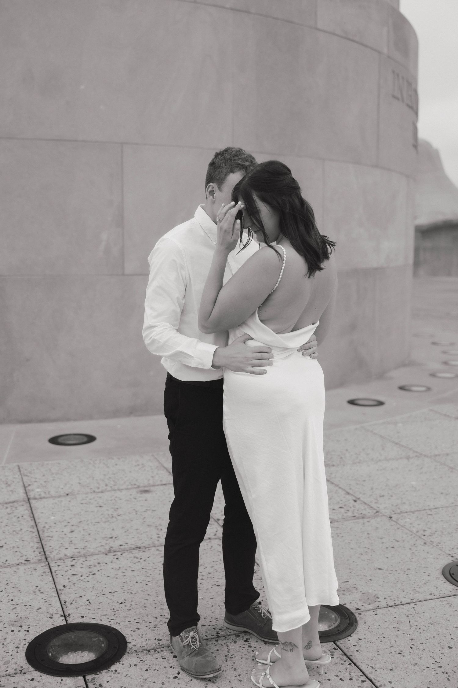 A romantic black and white photo sequence shows a couple sharing an intimate kiss against a stone wall.