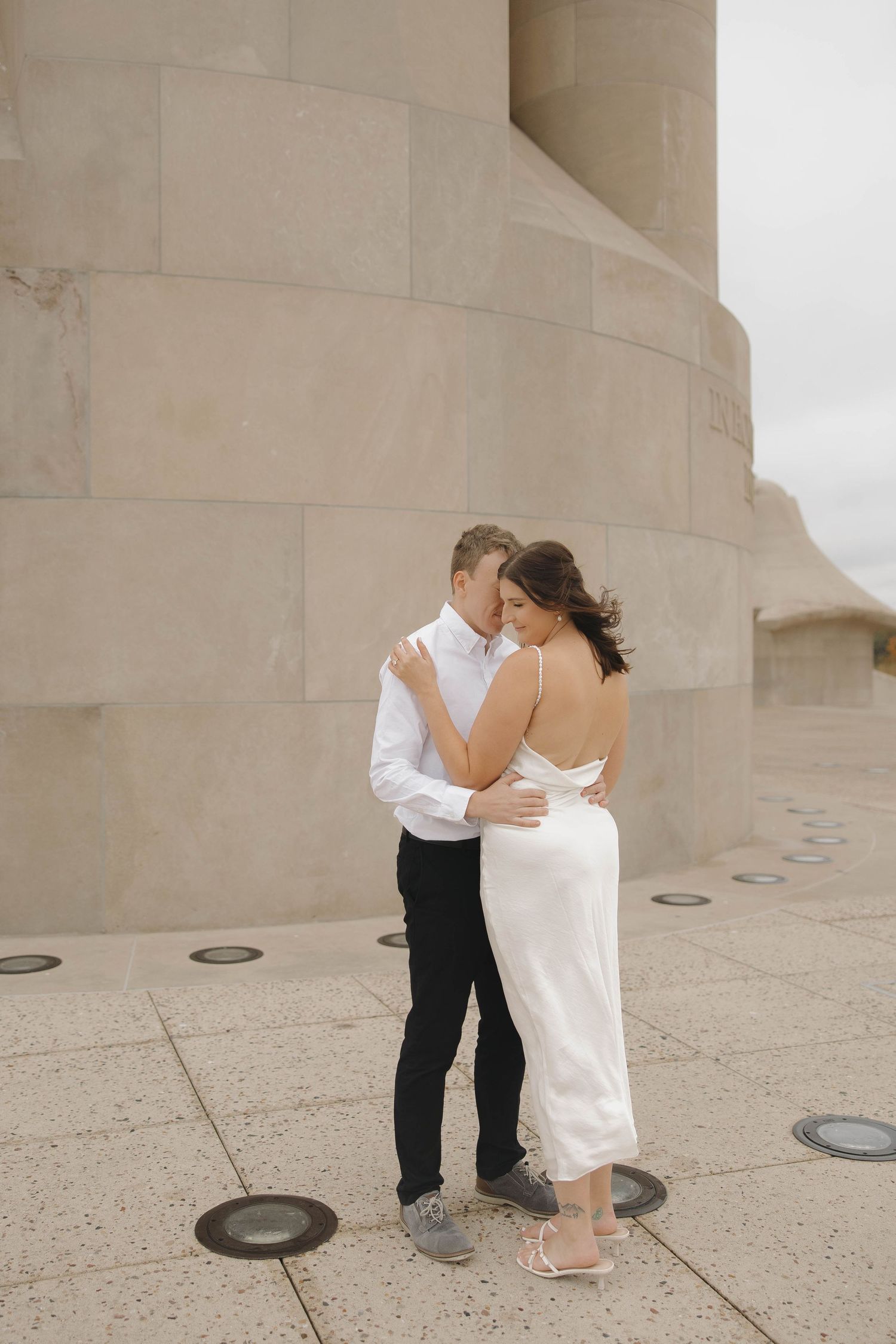 A couple shares an intimate dance moment on a concrete terrace with curved architectural details.