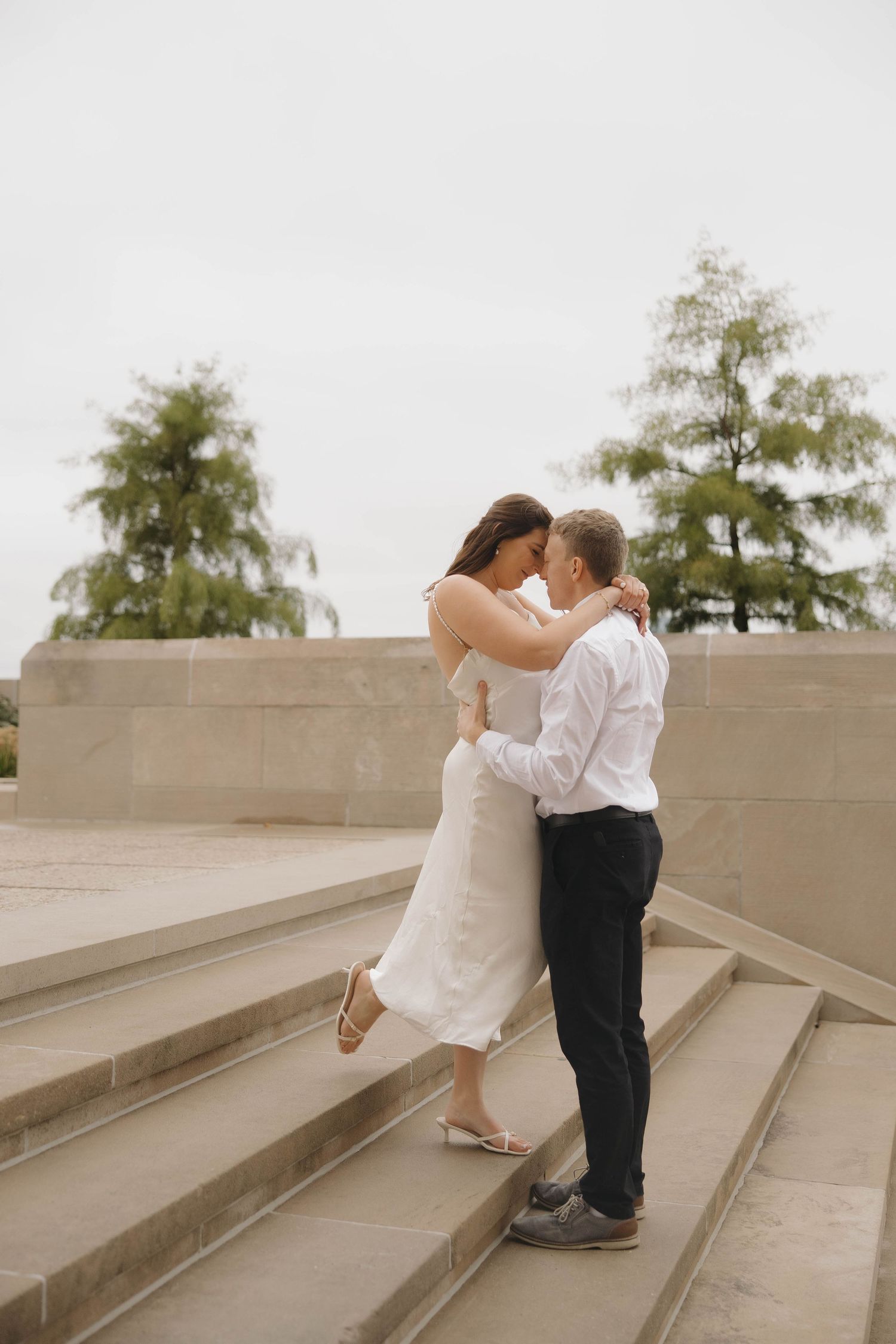 A romantic couple sharing intimate moments on concrete steps outdoors.