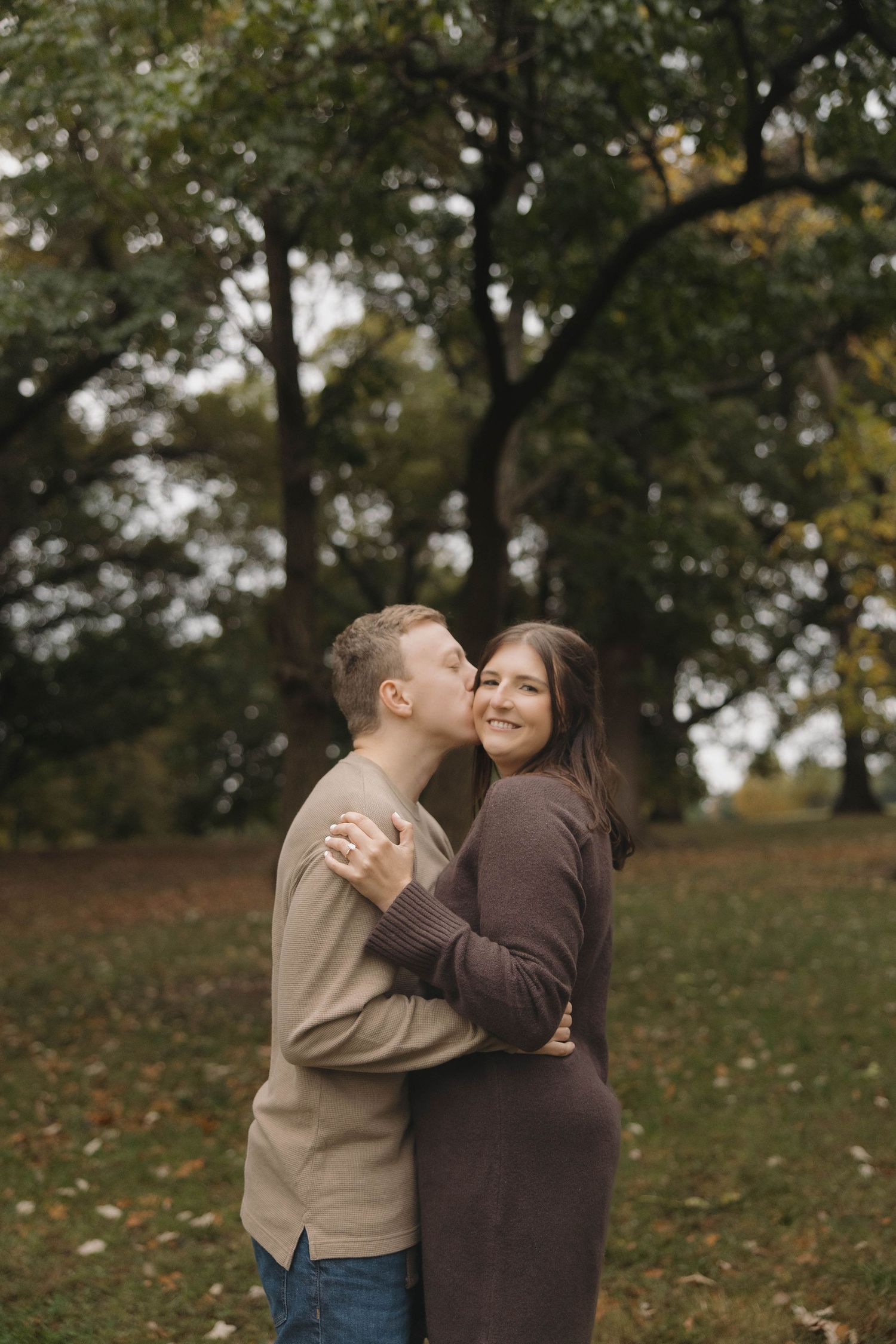 Couple shares joyful laughter together on an autumn day with fallen leaves.
