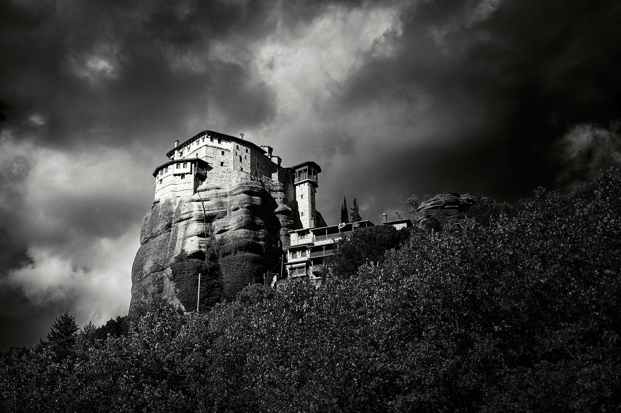 Dramatic black and white photos show an abandoned house on a hilltop against dark stormy skies.