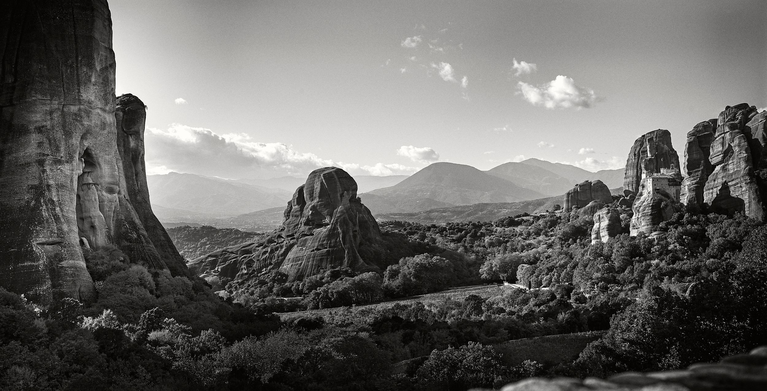 A panoramic black and white landscape view of rugged mountain peaks and valleys in a dramatic natural setting.