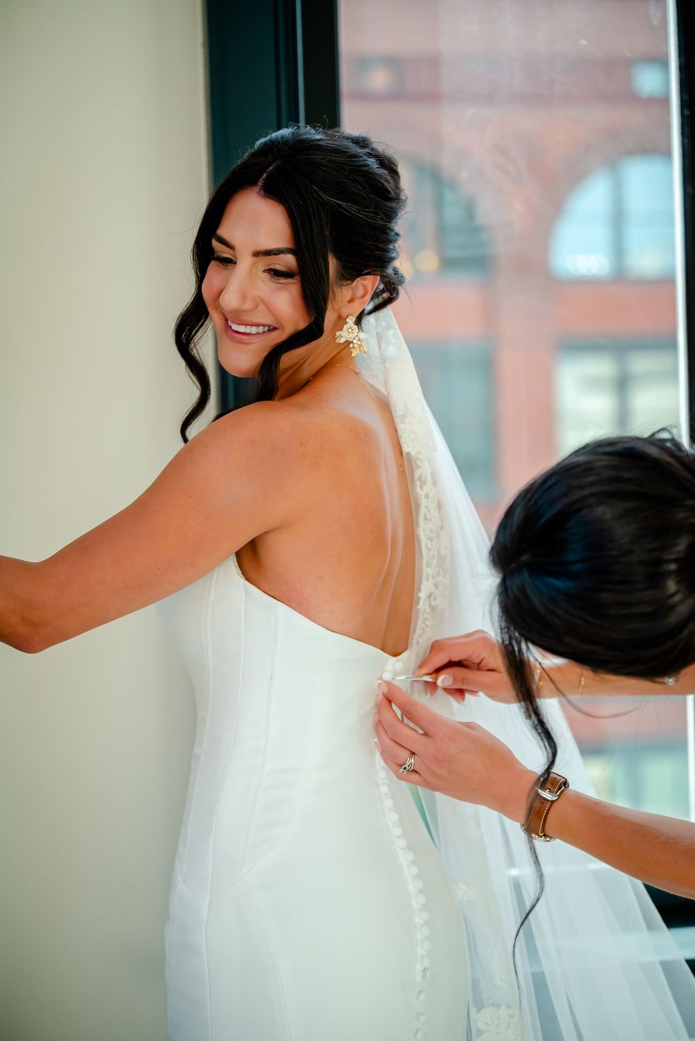 Series of photos showing a bride getting her wedding dress buttoned up and adjusted from behind.