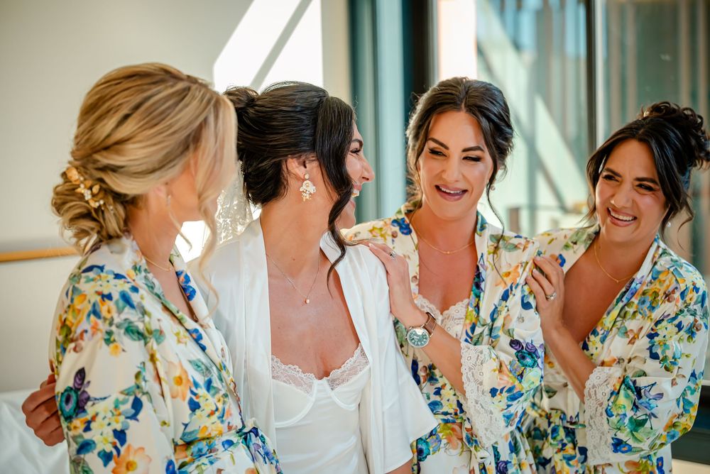 A group wearing matching floral robes gather together in a bright room during pre-wedding preparations.