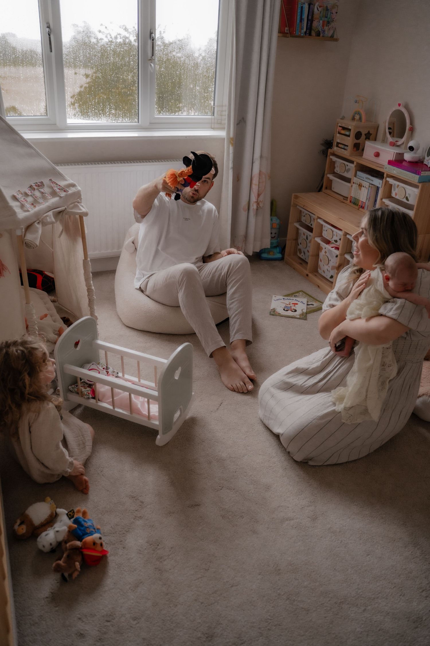 A person in white clothing sits in a cozy reading nook by a window with natural light streaming in.