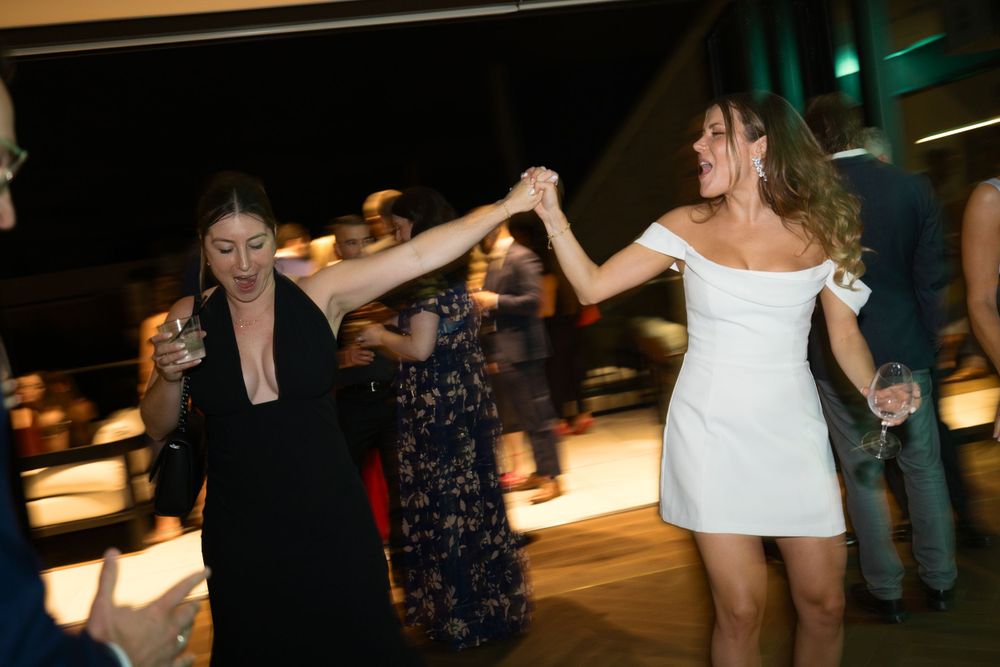 People dancing together at a celebration with a person in a white dress and others enjoying the festive atmosphere.