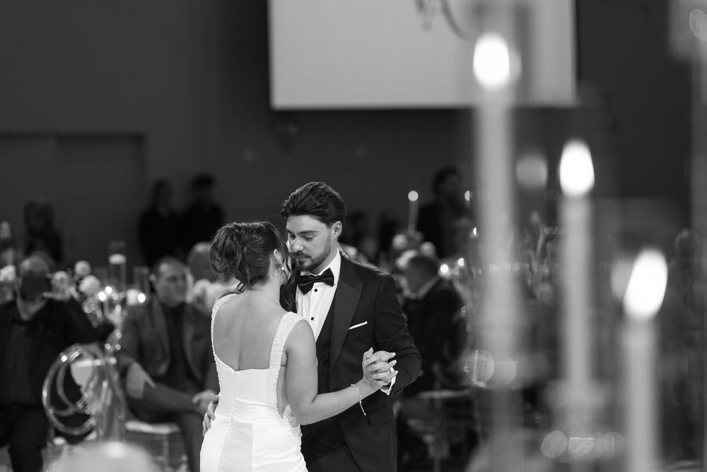A couple dances closely together on a dimly lit dance floor during what appears to be a romantic celebration.