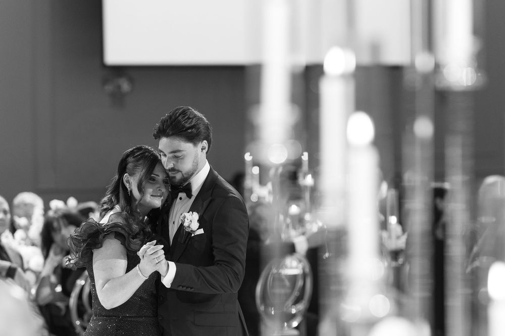 A black and white photograph shows a couple dancing together in an elegant ballroom setting.